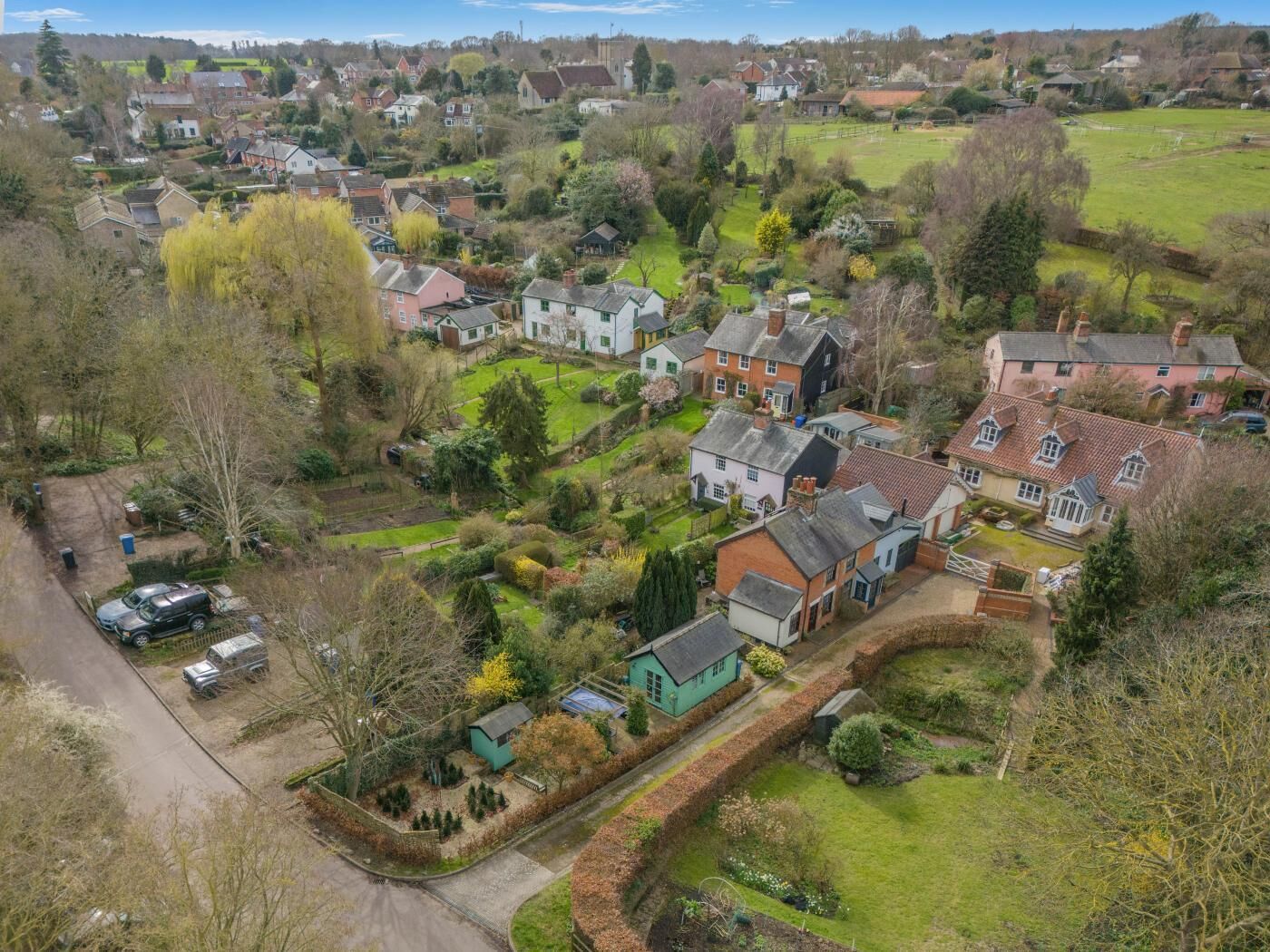 An aerial view of a residential area with houses, gardens, and a road.