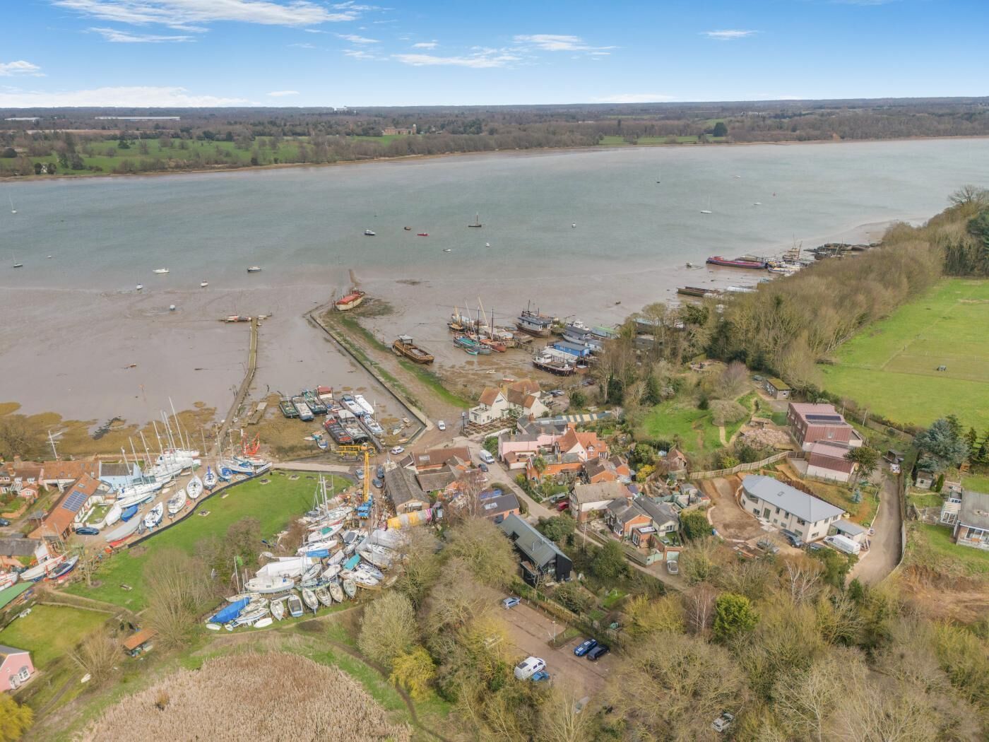 An aerial view of a coastal town with a marina, houses, and boats.
