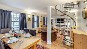 A dining area with a wooden table set for four, a sofa, and a spiral staircase. - 4 Bed in Braunton (oc-n34220) (Braunton)