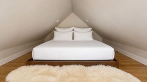 A bedroom with a bed, two pillows, a fluffy rug, and recessed lighting.