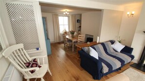 A living room with a sofa, a chair, a dining table, and a kitchen area. - 2 Bed in Mumbles (oc-hh132) (The Mumbles)
