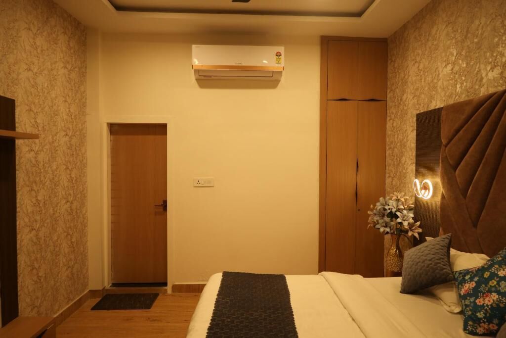 Un dormitorio con cama, mesita de noche y aire acondicionado de pared, además de una puerta.