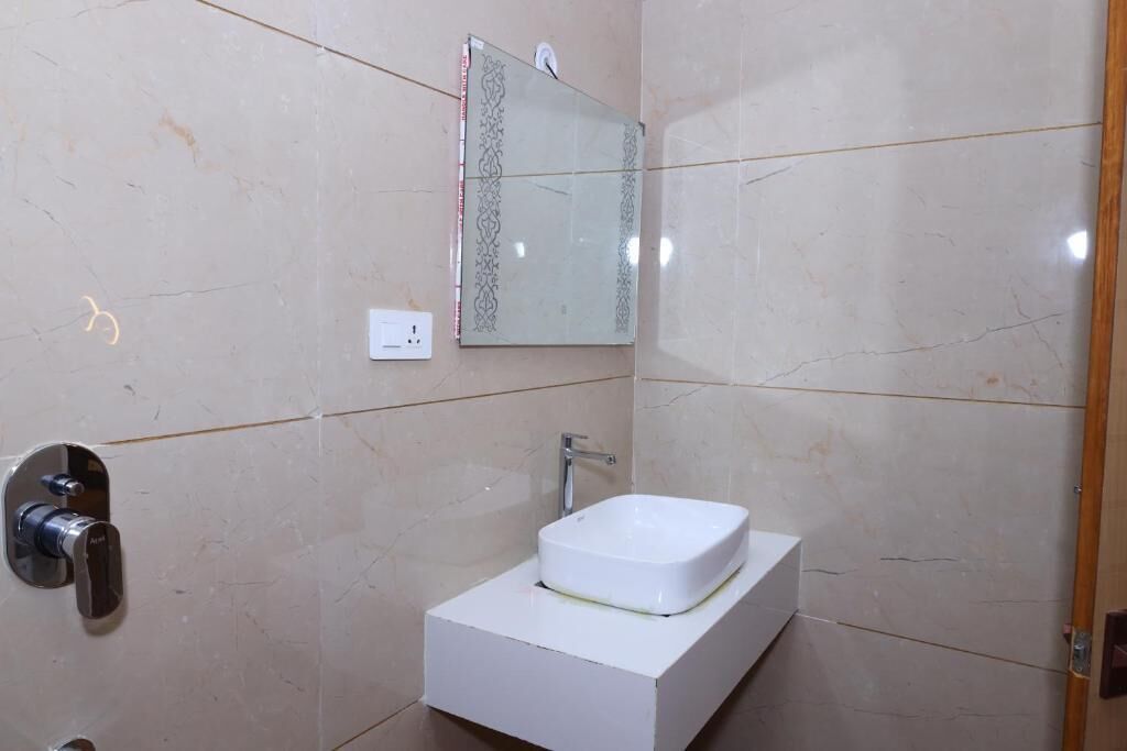 Un baño con un lavamanos blanco, un espejo y una ducha.