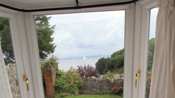 Una finestra a bovindo con vista su un giardino e uno specchio d'acqua.