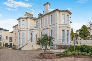 A multi-story building with a central staircase, a stone facade, and a landscaped courtyard. - 3 Bed in Torquay (oc-r34662) (Torquay)