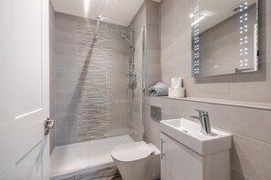 A modern bathroom with a glass shower enclosure, a toilet, a sink with a mirror, and a towel rack. - 3 Bed in Torquay (oc-r34662) (Torquay)