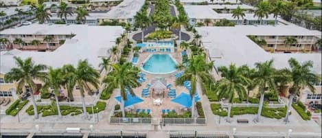 A resort with a central pool, palm trees, and a marina.