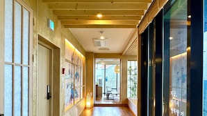 Un couloir doté d’un plancher en bois, d’une porte en verre et d’un mur orné d’œuvres d’art.