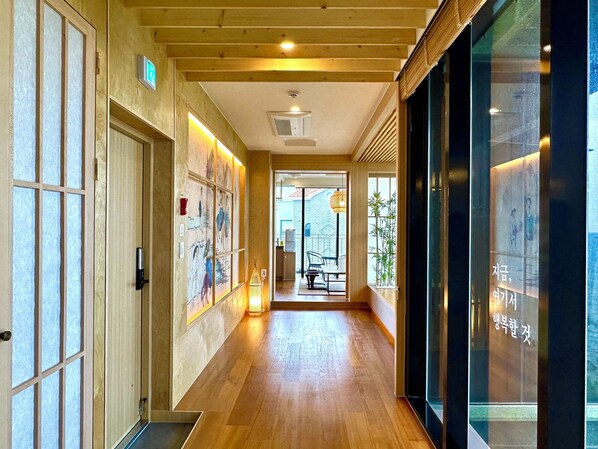 Un couloir doté d’un plancher en bois, d’une porte en verre et d’un mur orné d’œuvres d’art.