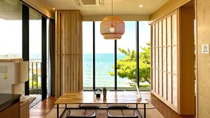 Une cuisine moderne dotée d’une grande fenêtre donnant sur la mer, de meubles en bois et d’un luminaire suspendu.