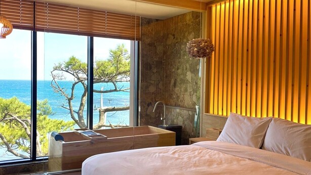 Une chambre avec une grande fenêtre, une baignoire et un mur en bois.