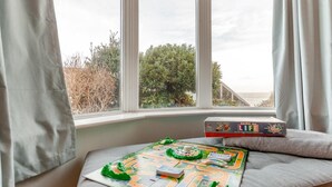 A game board on a window seat with a view of trees and the sea. - 3 Bed in Ilfracombe (oc-s34501) (Ilfracombe)