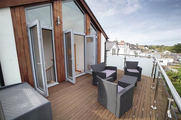 A balcony with wicker furniture and glass doors.