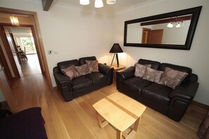 A living room with two leather sofas, a wooden coffee table, and a floor lamp.