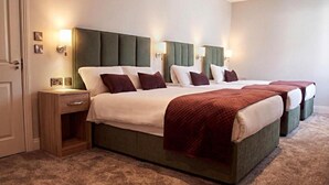 A hotel room with a large bed, bedside tables, and wall-mounted lamps. - Kerry Coast Hotel (Cahirciveen)