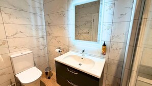A bathroom with a toilet, sink, and mirror. - Kerry Coast Hotel (Cahirciveen)