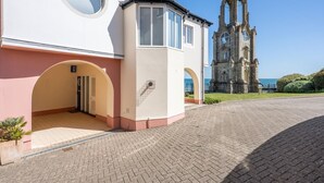 A building with a large clock tower in the background, a covered entrance, and a paved driveway. - 2 Bed in Swanage (oc-t34732) (Swanage)