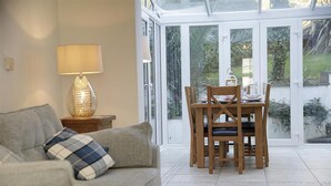 A living room with a sofa and a table set for dining, a lamp, and a view through a glass door. - 4 Bed in Gower (oc-hh672) (Horsham)