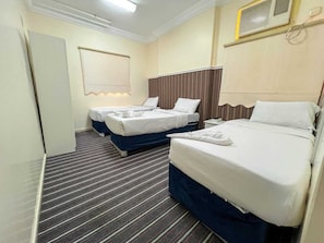 Quarto de hotel com duas camas, carpete listrado, janela com persianas e ar condicionado fixado na parede.