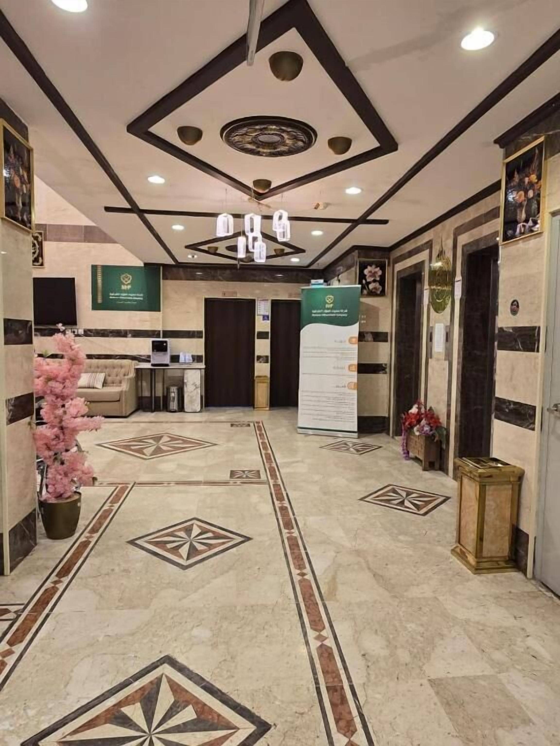 A hotel lobby with a reception desk, a decorative staircase, and a patterned floor.