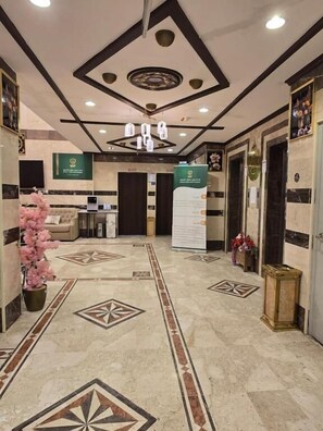 Un hall de hotel con una mesa de recepción, una escalera decorativa y un suelo estampado.