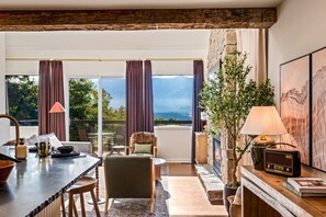 A modern room with a dining area, a fireplace, and a view of the outdoors. - 1BR Romantic Getaway | Hot Tub + Epic Views (Gatlinburg)
