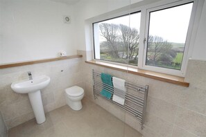 A bathroom with a white sink, toilet, and a towel rack with a towel. - 4 Bed in Gower (oc-hh45) (Pilton Rhossili)