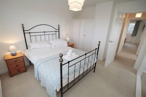 A bedroom with a bed, bedside tables, a wardrobe, and a door leading to another room. - 4 Bed in Gower (oc-hh45) (Pilton Rhossili)