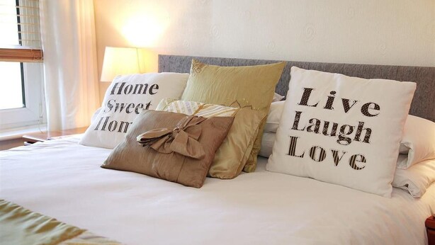 Una cama bien hecha con almohadas decorativas y una lámpara.