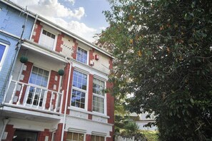 Ein zweistöckiges Gebäude mit einem Balkon und einem Baum davor.