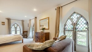 Ein Schlafzimmer mit Bett, Kommode, Spiegel und Fenster mit Blick.