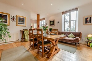 Een zithoek met een houten tafel en stoelen, een bank en een radiator.
