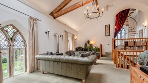 Ein geräumiges Wohnzimmer mit einer Ledersofa, einer Holztreppe und einem Chandelier.