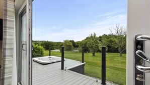 Una terraza con hidromasaje, vista a un área verde y cielo despejado.