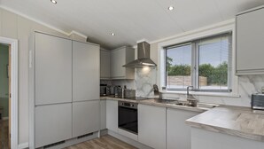 Una cocina moderna con electrodomésticos integrados, una ventana con persianas y suelo de color claro.