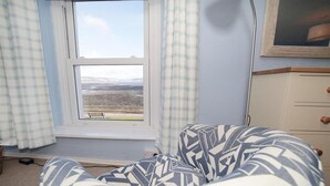Una habitación con ventana que ofrece vista a un paisaje, una silla con diseño y un aparador con cajones.