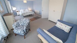 Un dormitorio con cama, una silla, armario y escritorio.