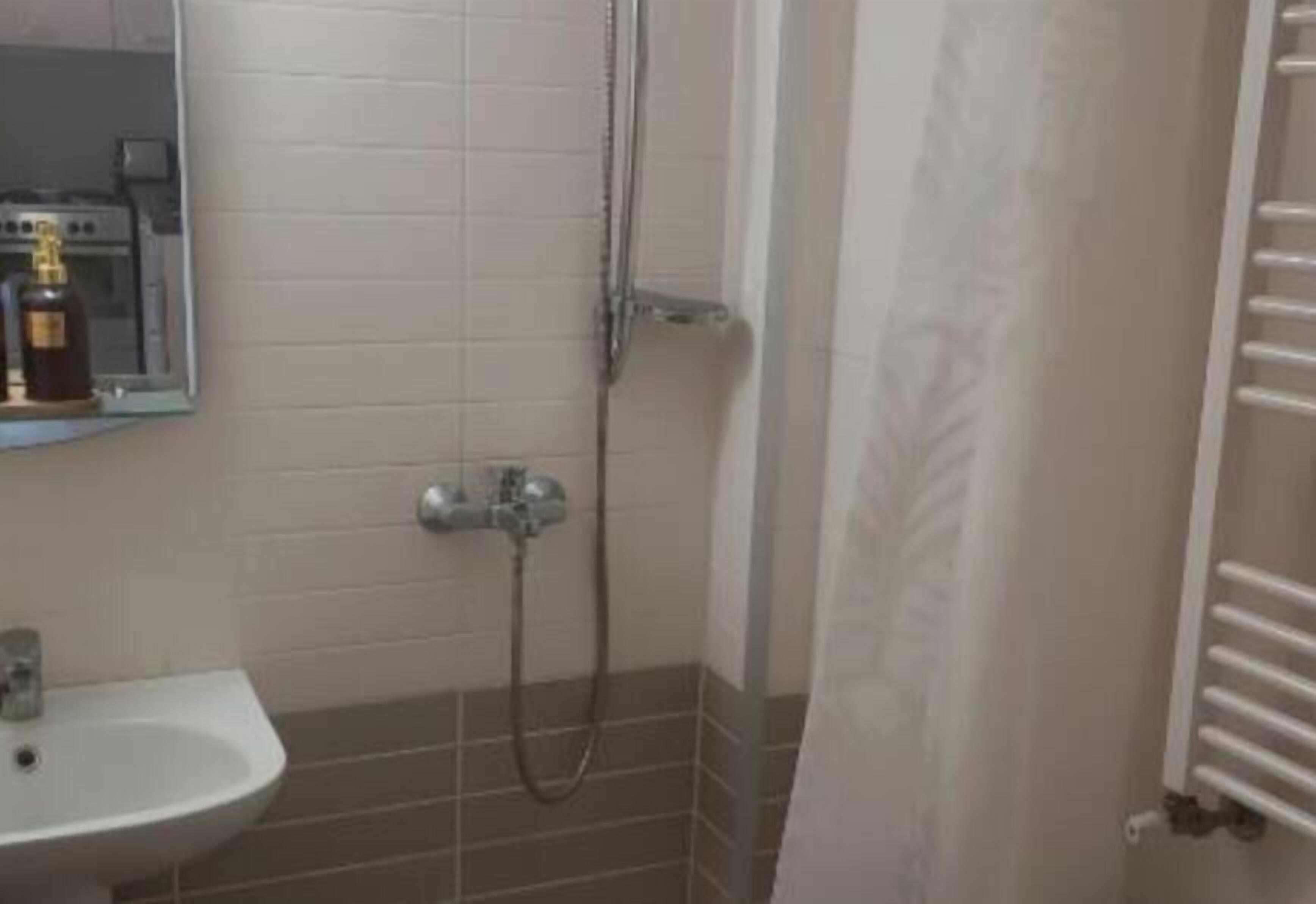 A bathroom with a sink, a shower, and a towel rack.