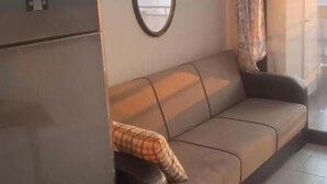 Ein Wohnbereich mit einer Couch, einem Spiegel und einem fenster mit Vorhängen.
