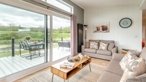 En rummelig stue med store glasdøre til en udendørs terrasse, en sofa og et sofabord.