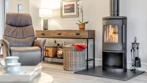 A cozy living room with a leather armchair, a wooden console table, wicker baskets, a fireplace, and framed pictures on the wall. - 2 Bed in Alnwick (oc-e34719) (Alnwick)