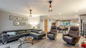 A modern living room with a sectional sofa, two recliners, a coffee table, and a dining area with a table and chairs. - 2 Bed in Alnwick (oc-e34719) (Alnwick)