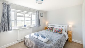 Een slaapkamer met een bed, een raam met gordijnen, een bedlamp en een radiator.