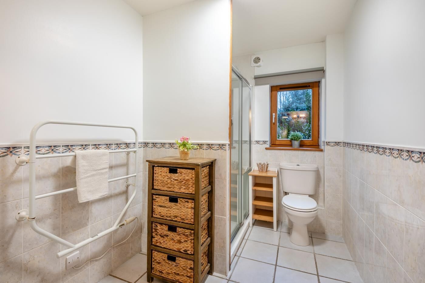 A bathroom with a shower, toilet, and a small window.