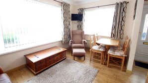 A room with a bench, a chair, a table, and curtains. - 2 Bed in Mumbles (oc-hh424) (The Mumbles)