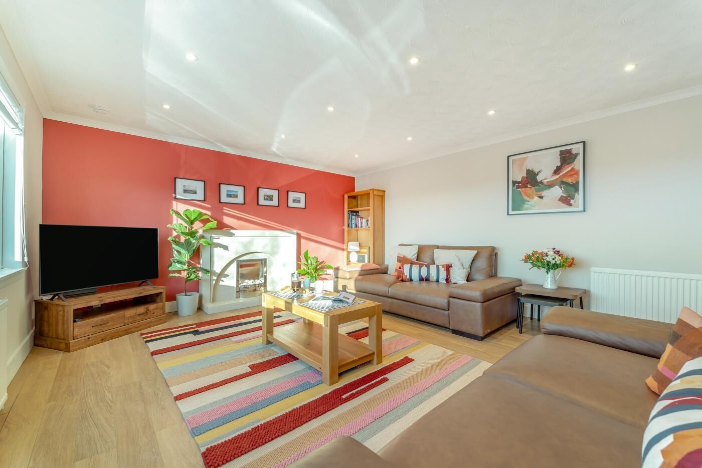 Ein Wohnzimmer mit Flachbildfernseher, Kamin, Sofa, Couchtisch und Bücherregal.