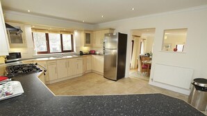 A modern kitchen with a central island, stainless steel appliances, and a dining area with a view. - 4 Bed in Langland (oc-hh36) (Newton)