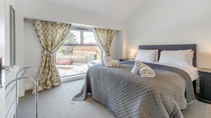Une chambre à coucher avec un lit, une fenêtre avec des rideaux, un radiateur et une vue sur l’extérieur.