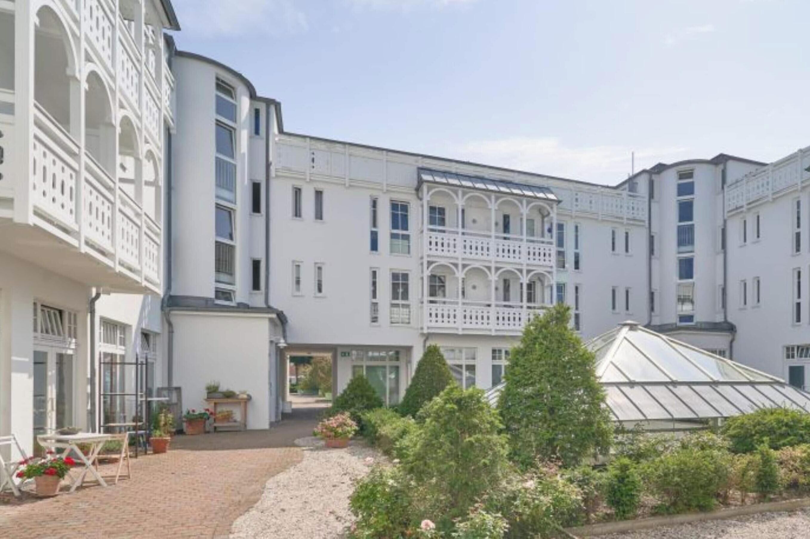 A white building with multiple balconies and a greenhouse.