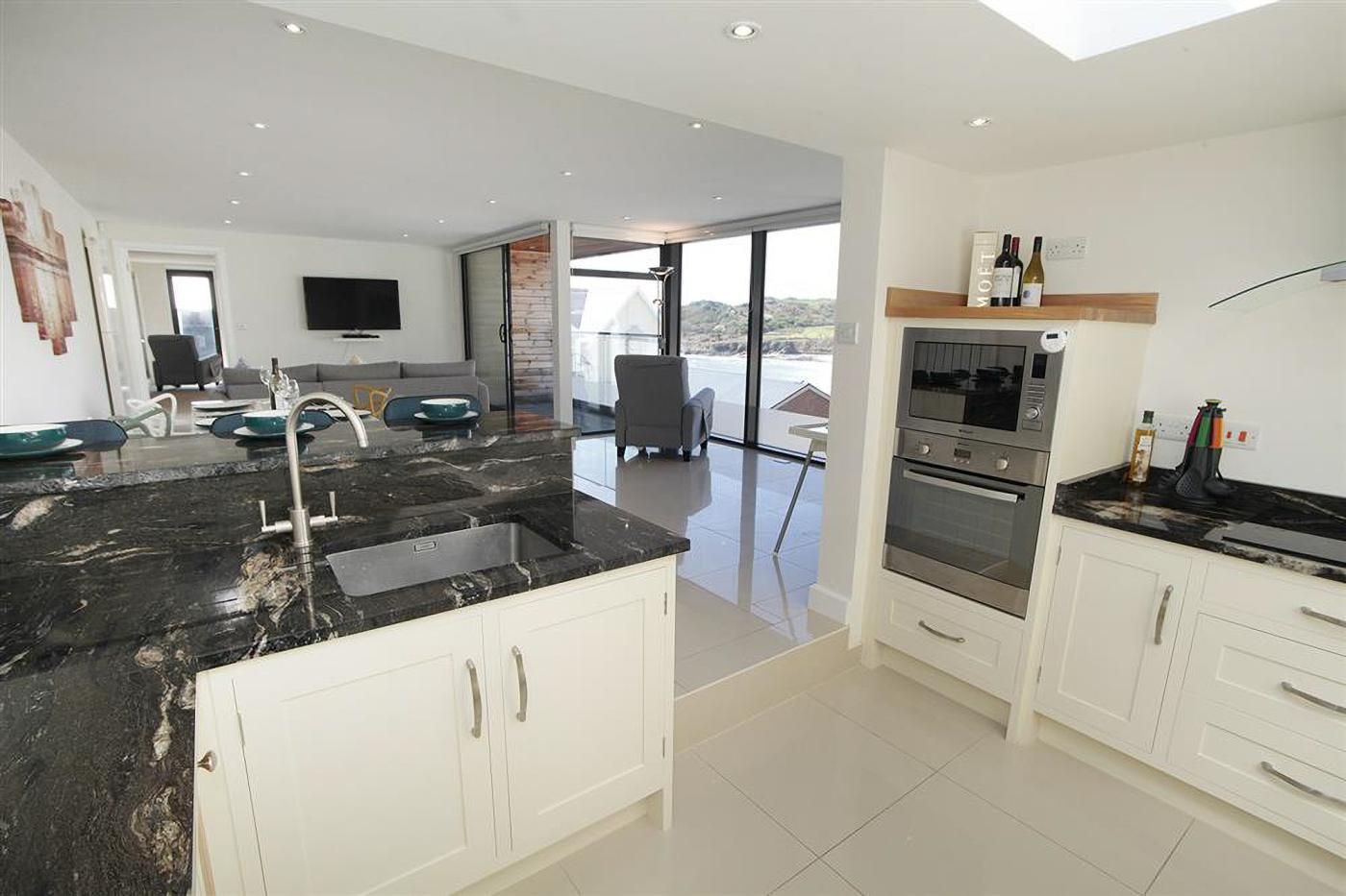 A modern kitchen with a large island, built-in oven, and a dining area with a view.